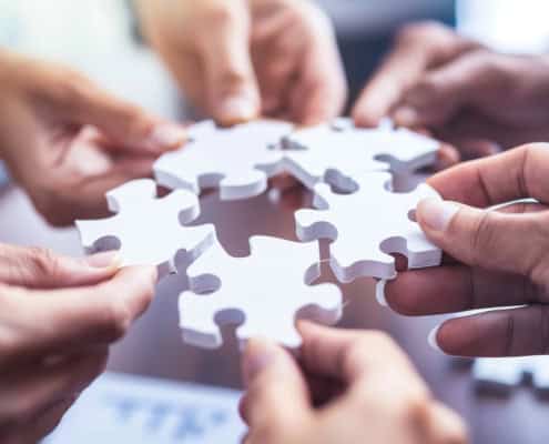 Wie Sie die Zusammenarbeit in Ihrem Unternehmen effektiv verbessern können 1 3D-Rendering Bild mit Händen, die Puzzleteile aneinanderhalten und damit Zusammenarbeit symbolisieren