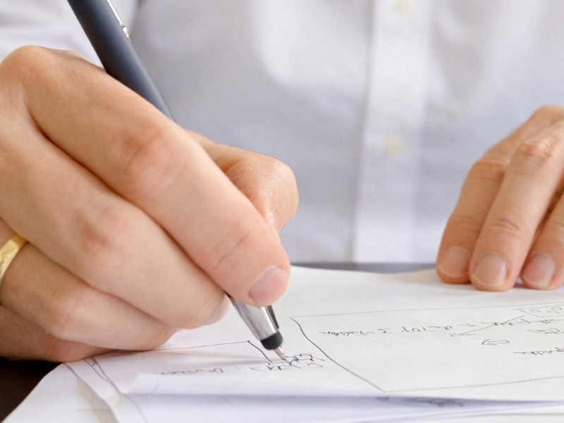 Hand mit Kugelschreiber beim Ausarbeiten von Stichpunkten