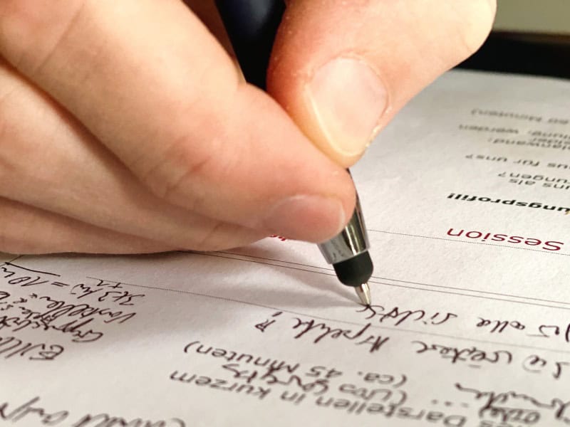 Nahaufnahme einer Hand mit Stift beim Arbeiten an Notizen